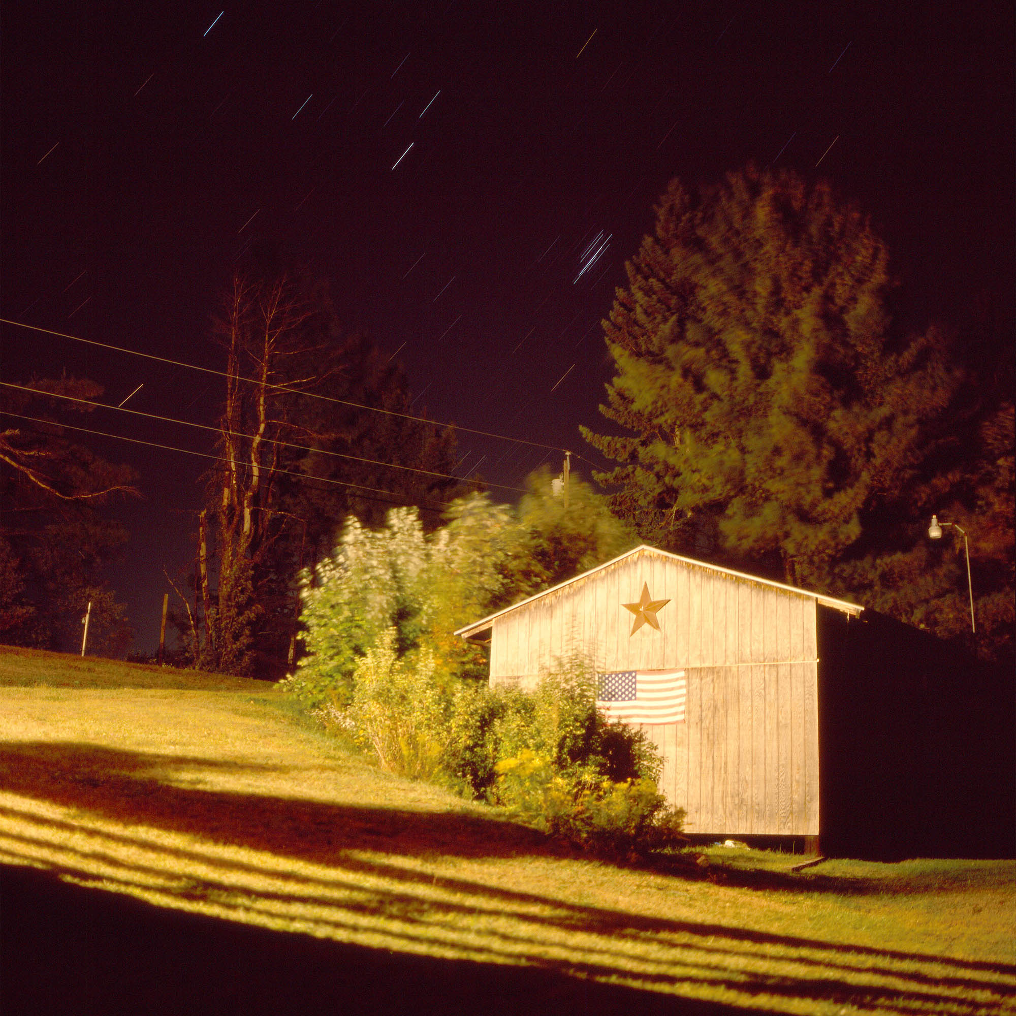 Star trails over a shed and trees